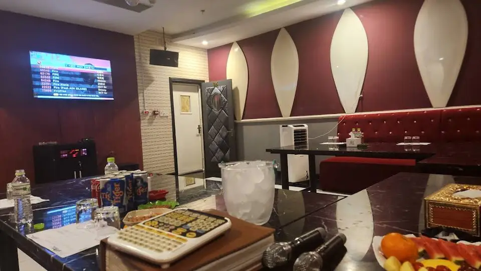 다낭 원오페라 가라오케 버건디 레드 벽면과 TV 노래방 시스템, 대리석 테이블 위에 음료와 마이크가 준비된 소형 가라오케 룸 내부