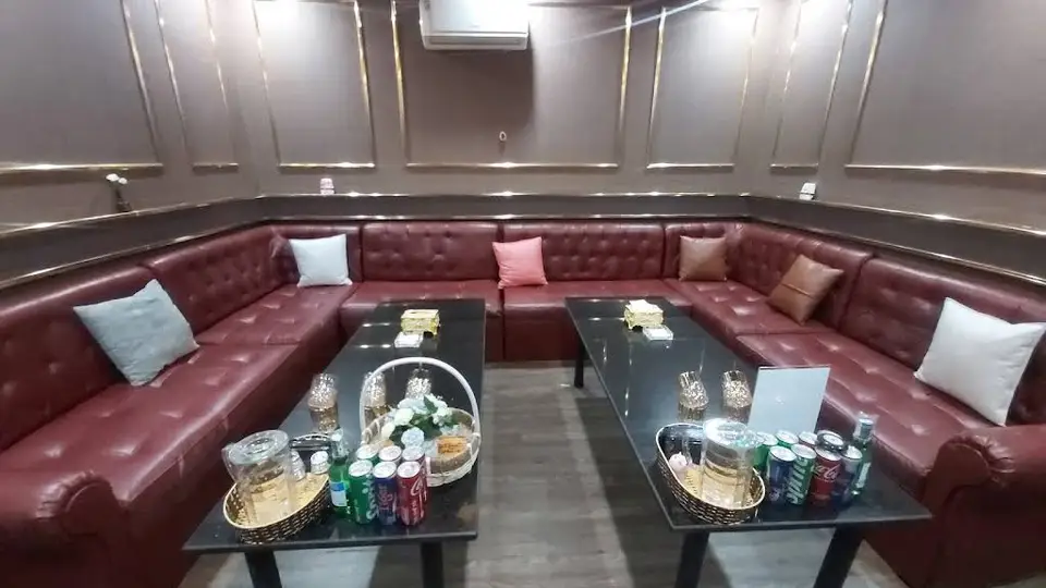 하노이 킹덤 가라오케 킹덤 가라오케의 넓은 U자형 레드 가죽 소파와 블랙 대리석 테이블, 고급 음료 세팅이 완비된 VIP 라운지 룸