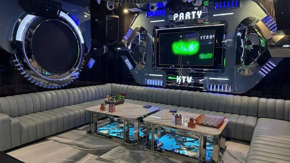하노이 비너스 가라오케 크롬 원형 프레임 스테이지와 PARTY·KTV 네온 사인, 그레이 채널 소파 및 마블 패턴 LED 내장 테이블이 갖춰진 스페이스 파티 룸