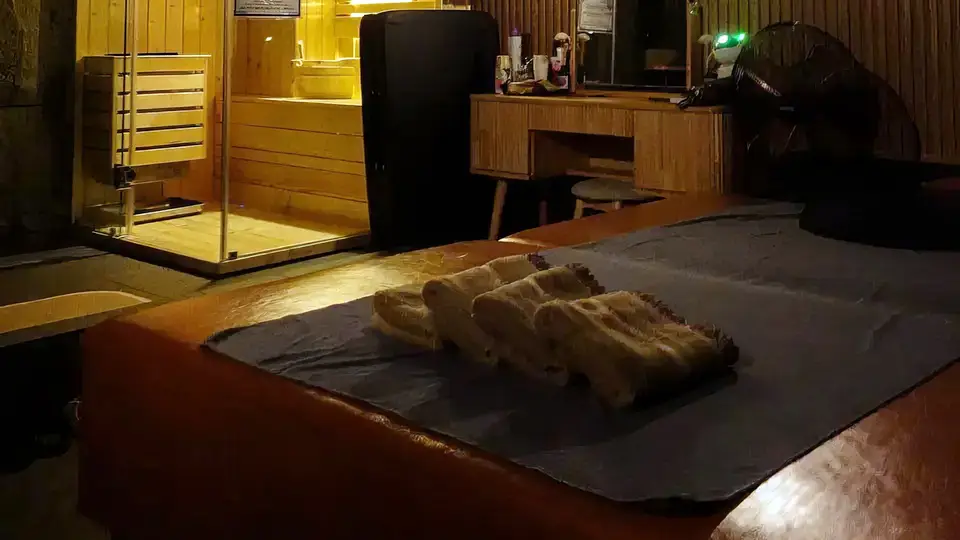 호치민 두리안 스파 사우나 부스와 가지런히 정돈된 타월이 놓인 마사지 베드, 빈티지 원목 드레서가 구비된 스위트 룸 내부