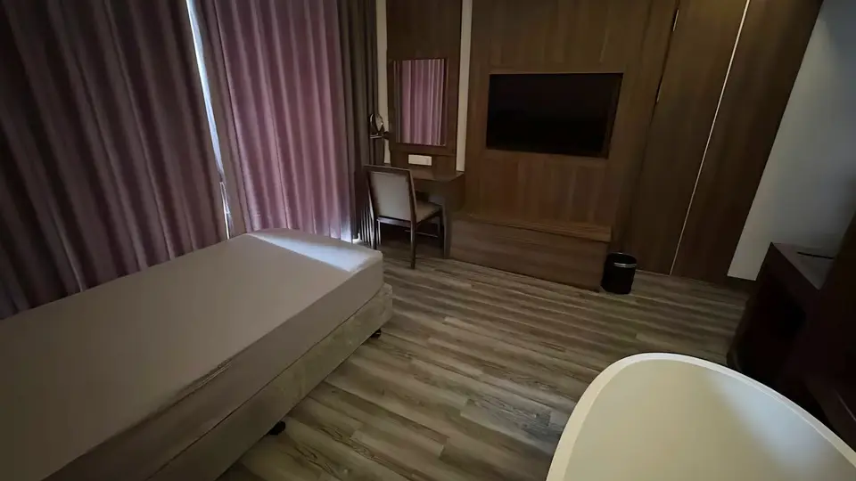 나트랑 클라우드 나인 우드 패널 벽면과 밝은 바닥재의 스파 룸, 싱글 마사지 베드와 벽걸이 TV, 독립형 욕조