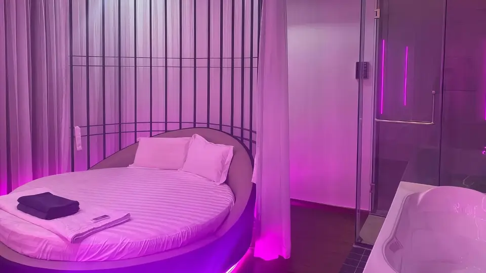 붕따우 도쿄 푸미 마사지 보랏빛 무드 조명 아래 대형 원형 침대와 유리 샤워 부스, 자쿠지 욕조가 배치된 VIP 스위트 룸